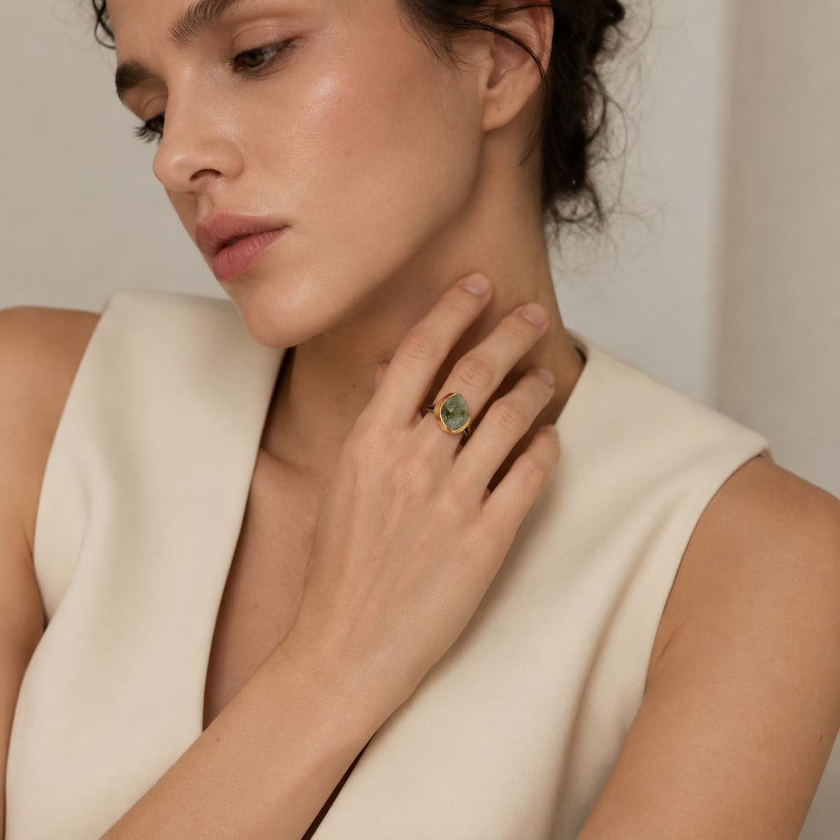 Gold-plated ring with a raw green amethyst center shown at an angle.