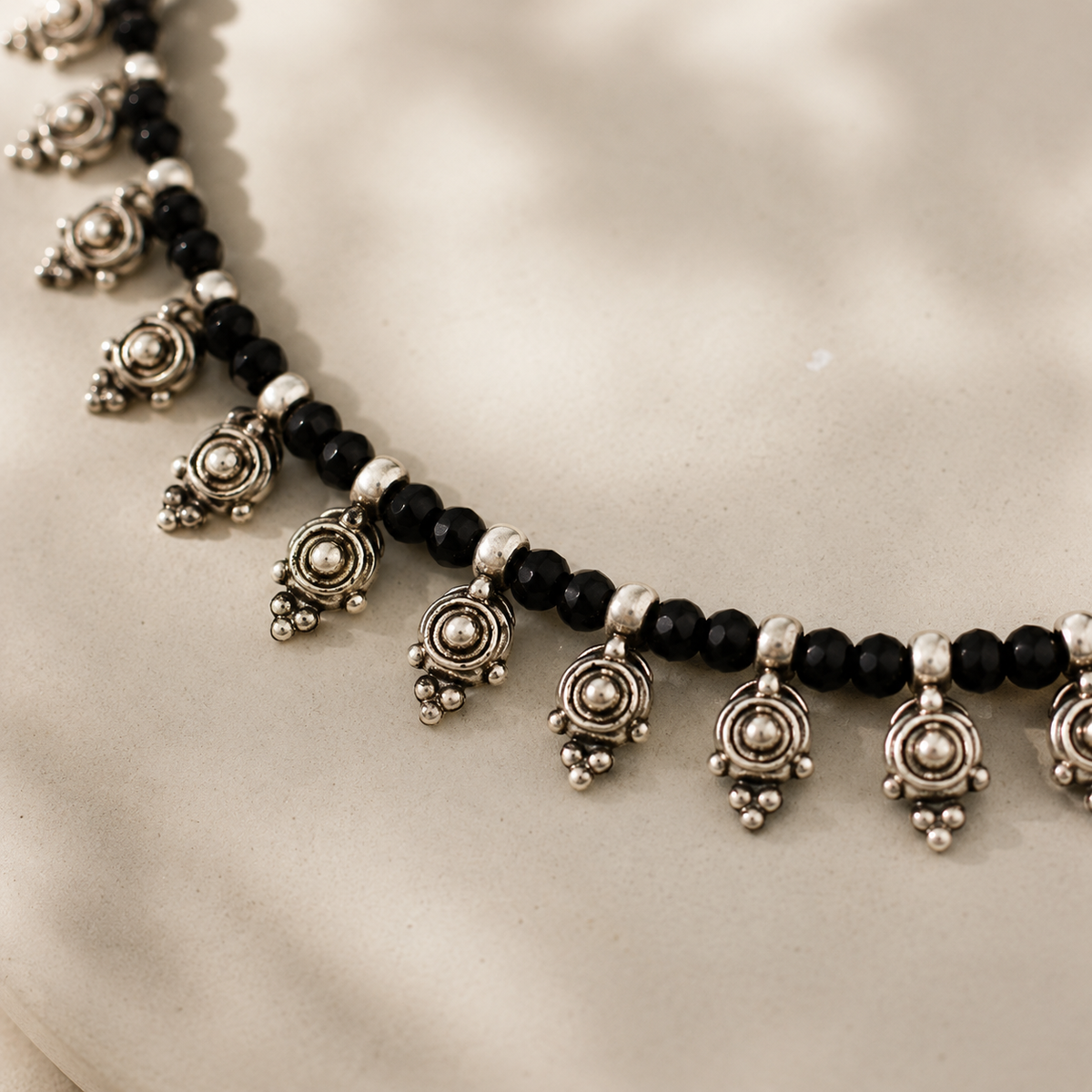Close view of the black beads and silver-tone pendant details.