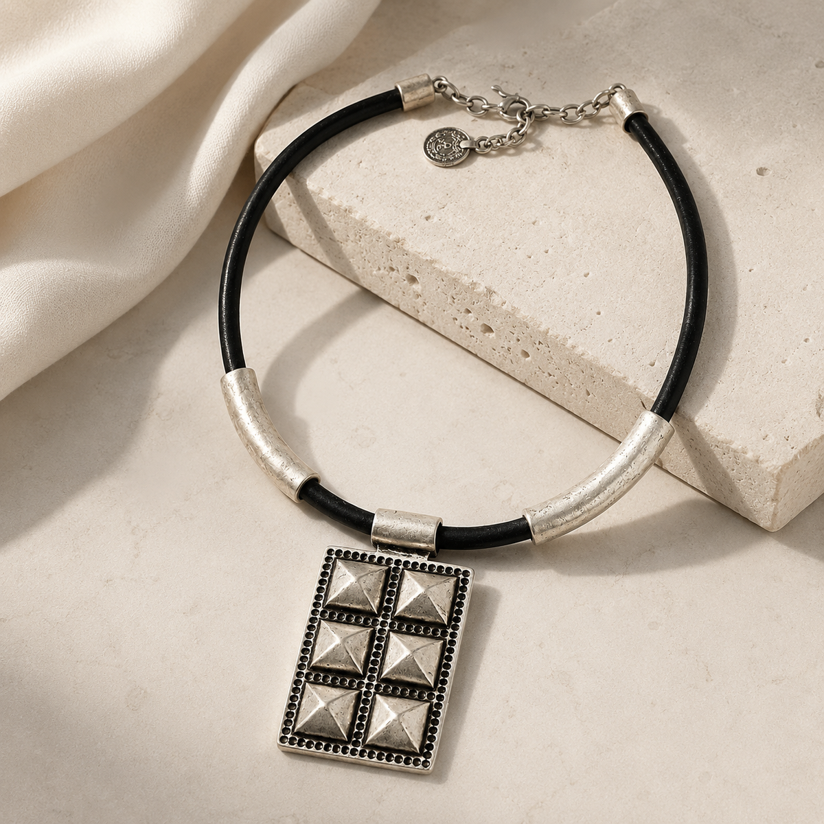 Black cord necklace with a bold geometric pendant and silver-tone finish.