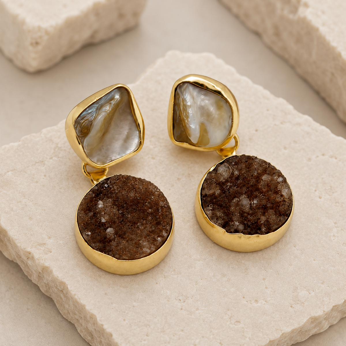 Angle view of gold-plated dangle earrings with black cluster drops.