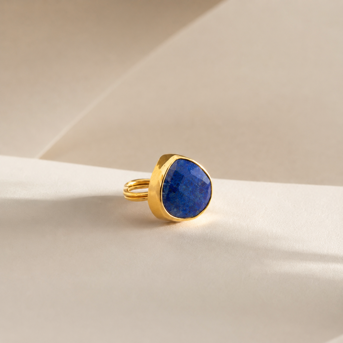 Angled view of a gold-plated lapis blue teardrop ring.
