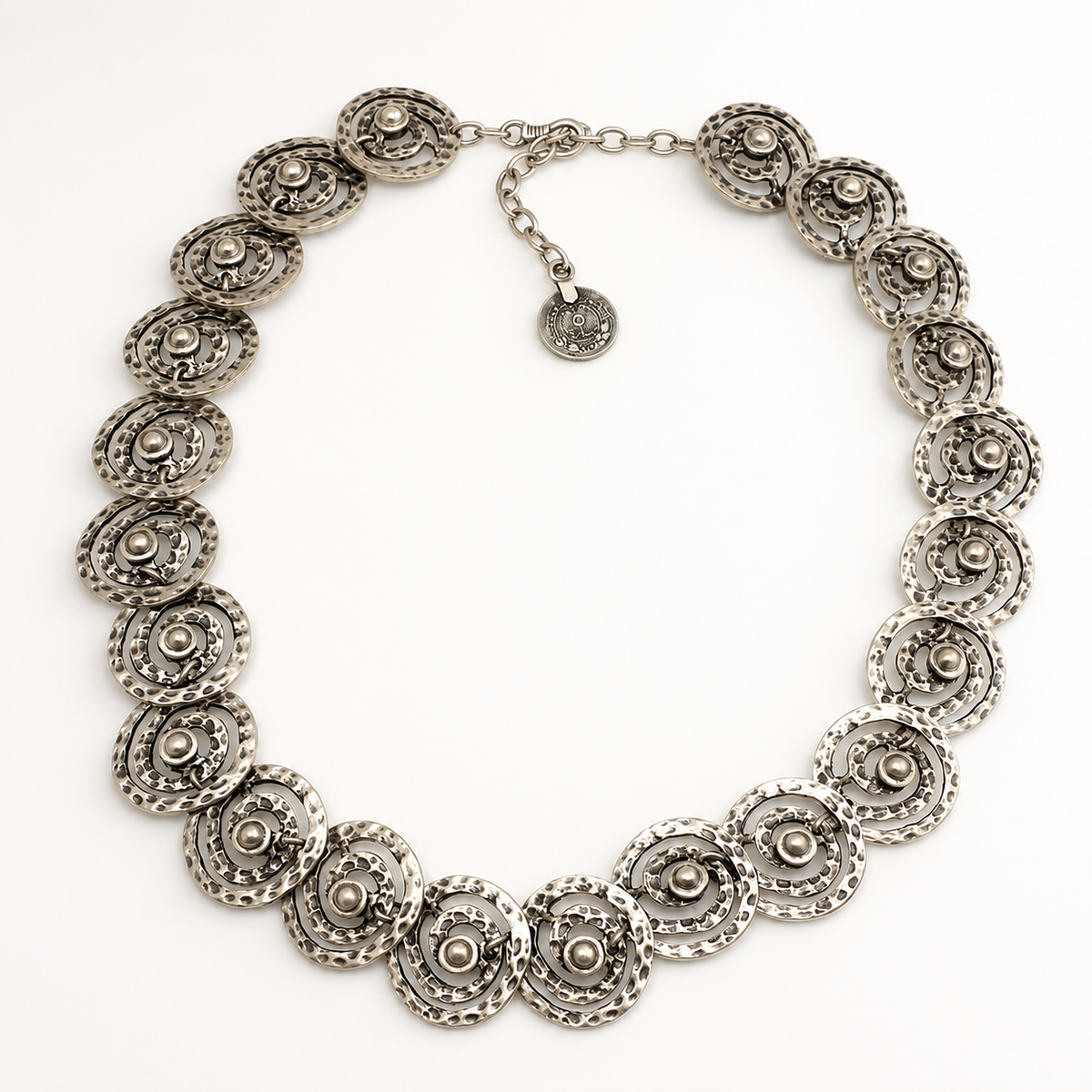Angle view of a silver-tone necklace with repeating spiral disc details.