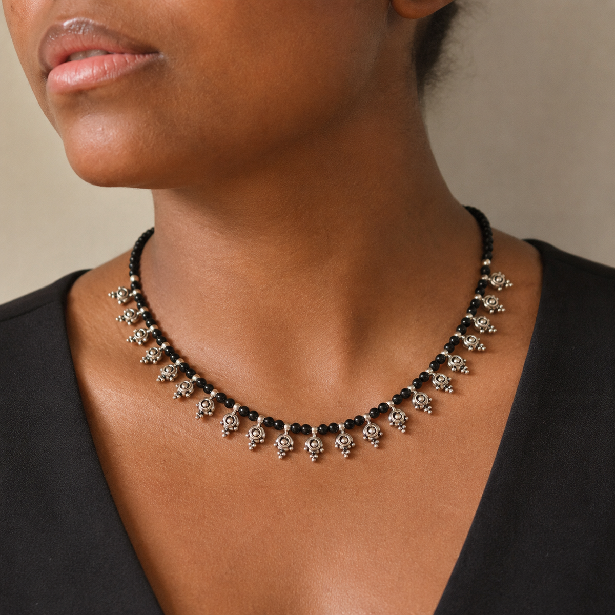 Black bead necklace with silver-tone dangle accents shown from the front.