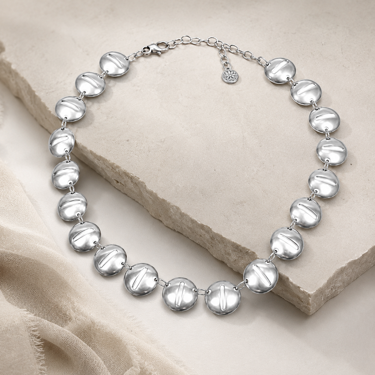 Angled view of a silver-tone round disc collar necklace with polished discs.