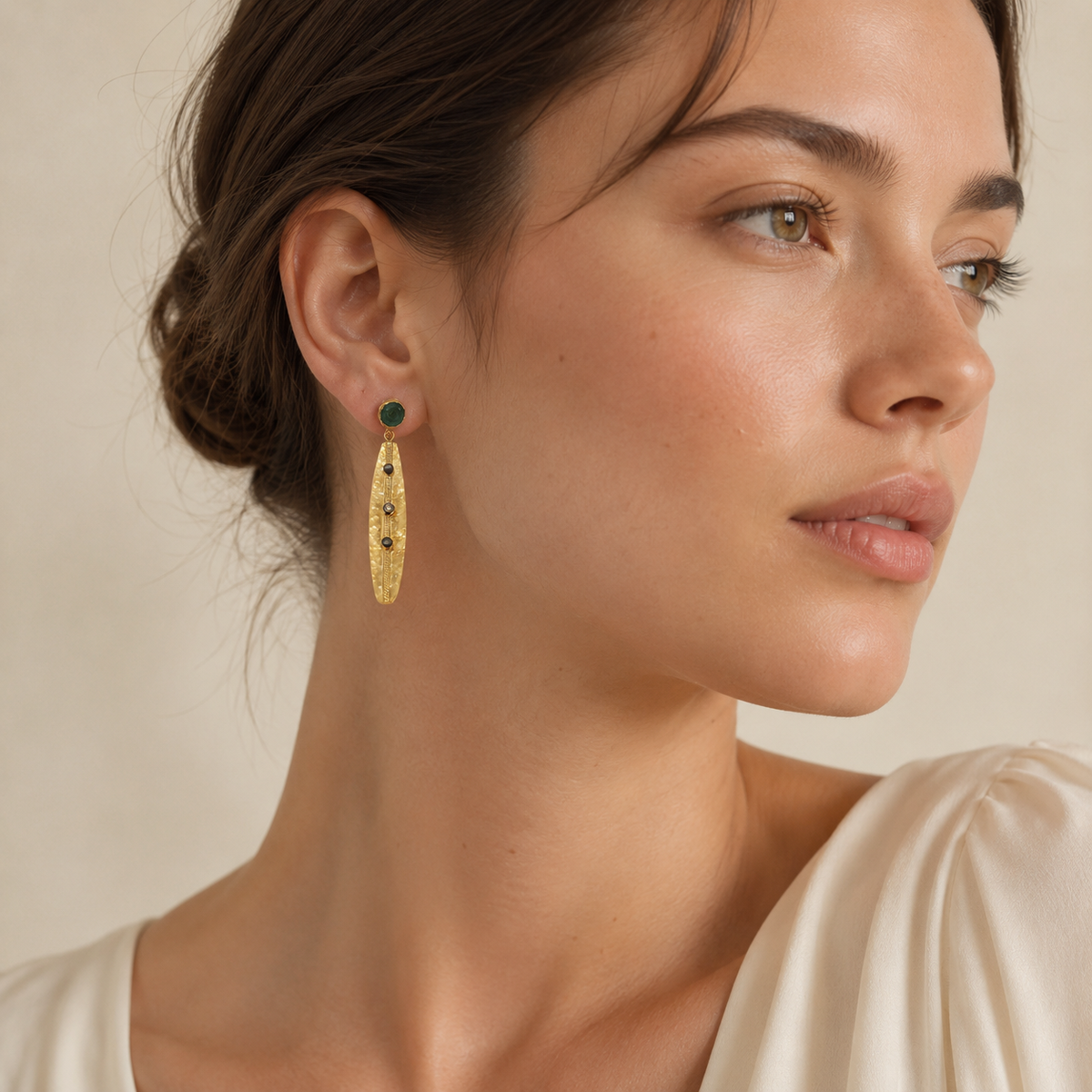 Pair of long gold-plated earrings with green stone tops and textured drops.
