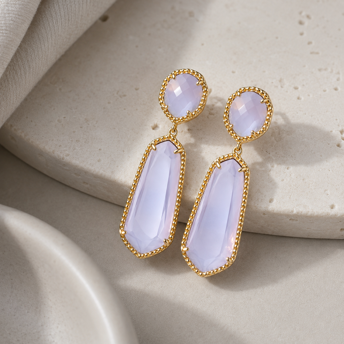 Angle view of lavender drop earrings with a gold-tone pave border.