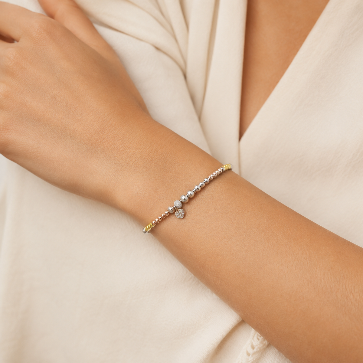 A bracelet with polished mixed-tone beads and a small heart charm.