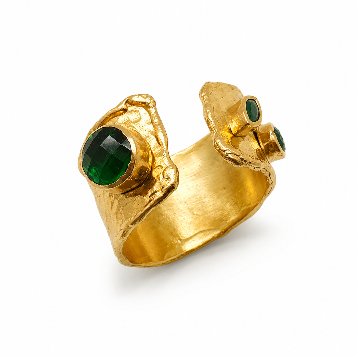 Gold-plated open cuff ring with emerald green stone accents and a textured sculptural shape.