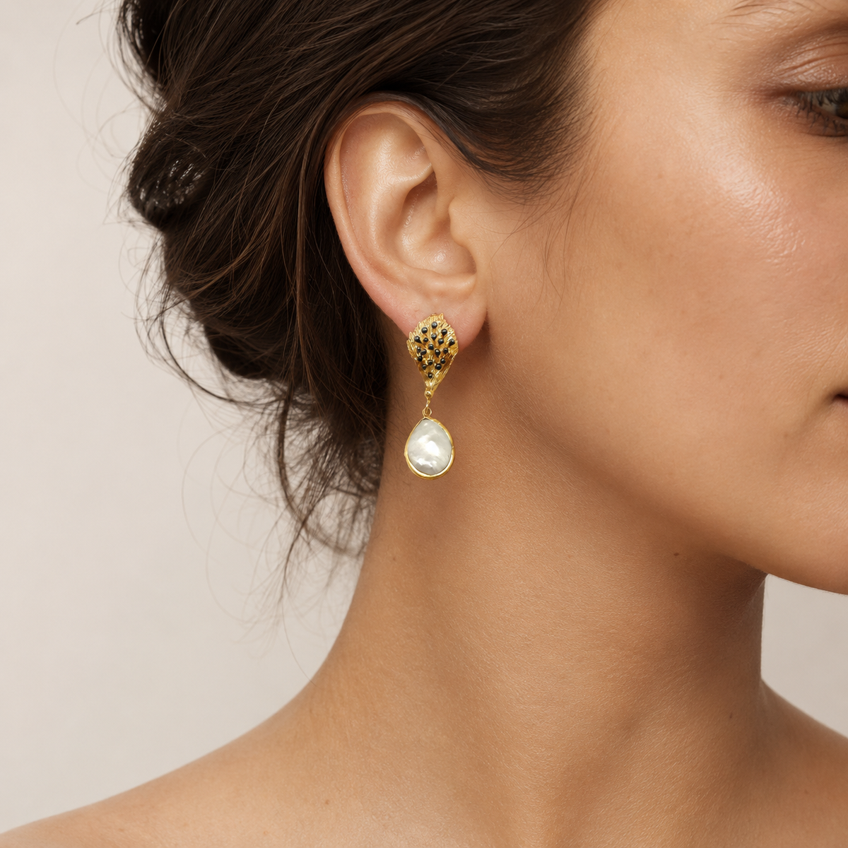 Gold-tone drop earrings with black bead details and smooth pearl-like teardrop pendants.