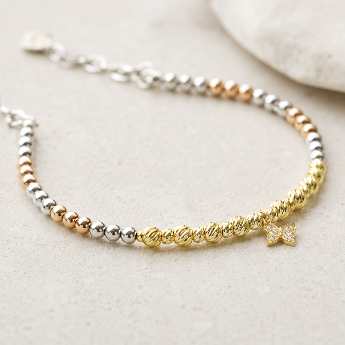 Close view of the bracelet showing polished beads and butterfly charm detail.