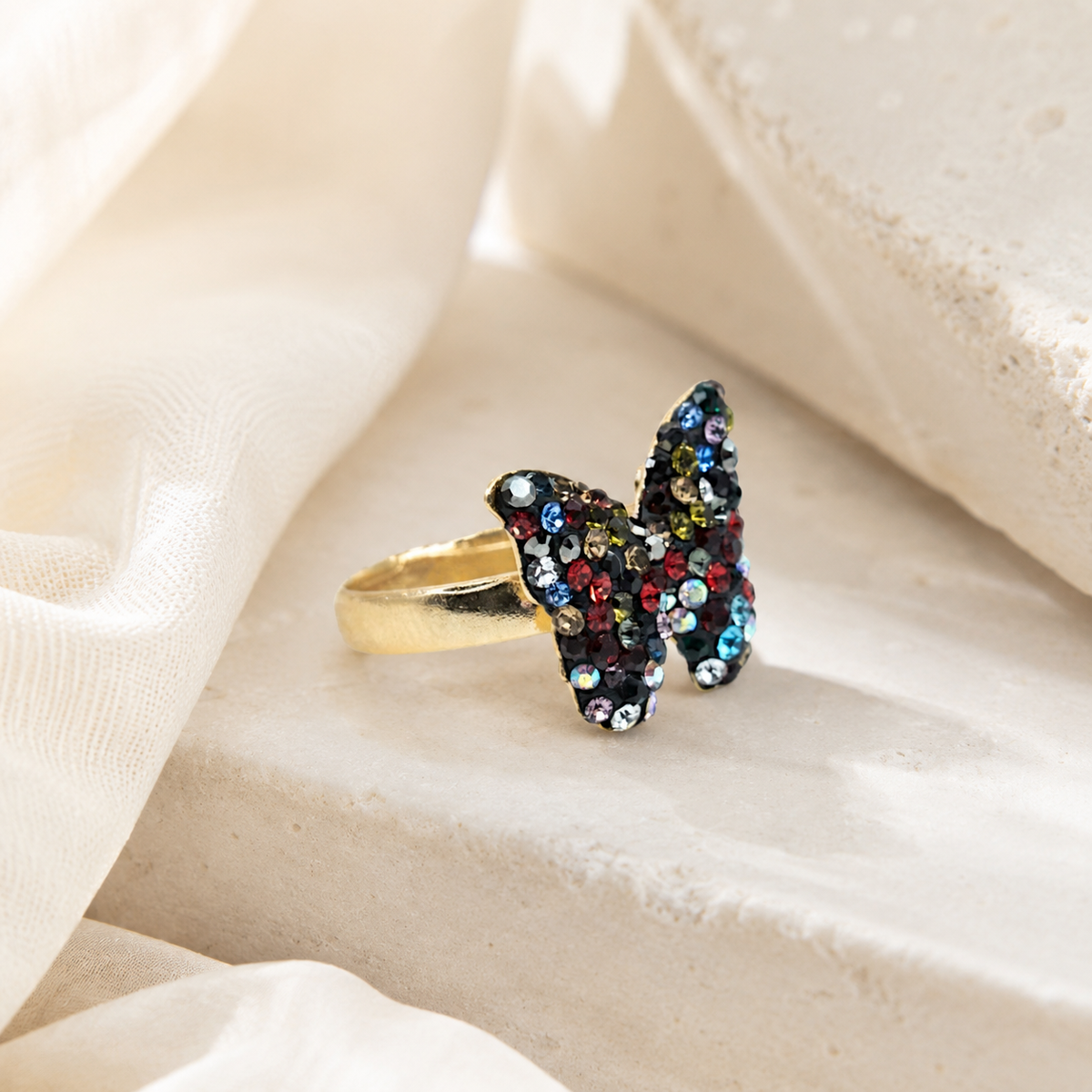 Gold butterfly ring with multicolor CZ stones styled on a white background.