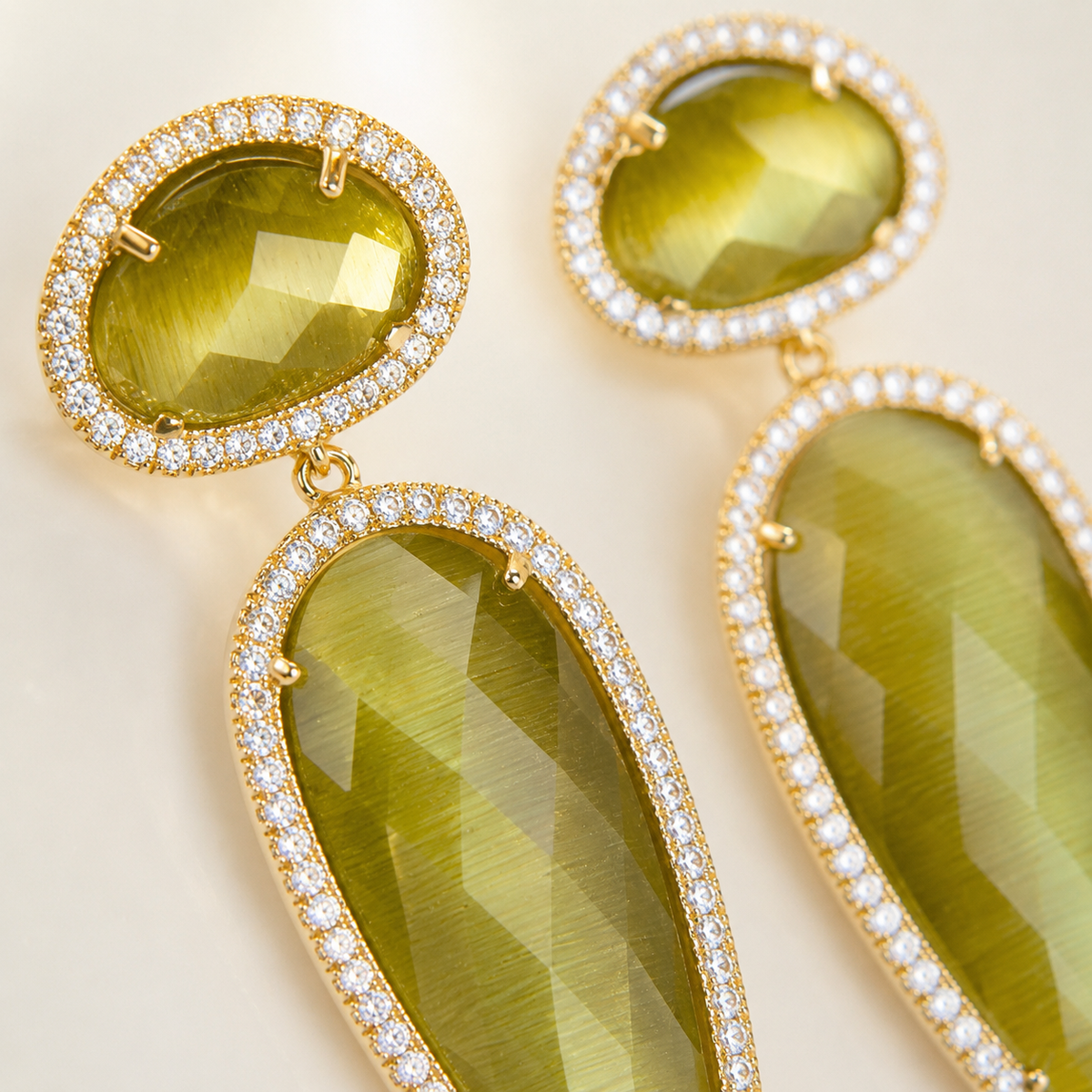 Close view of olive cat eye stones set in gold-plated teardrop earrings.