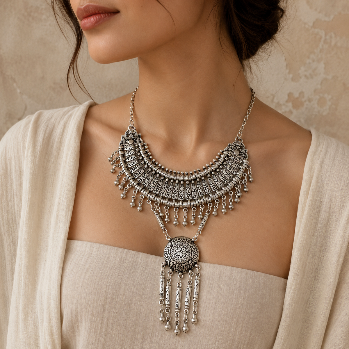 Silver-tone necklace with ornate fan details and a round pendant.