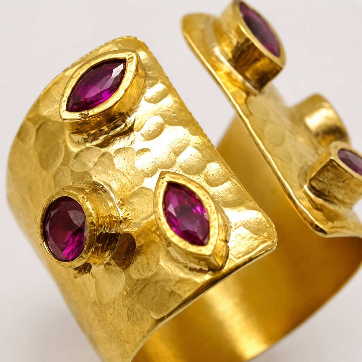 Close view of the hammered gold-plated texture and cherry-toned stones.