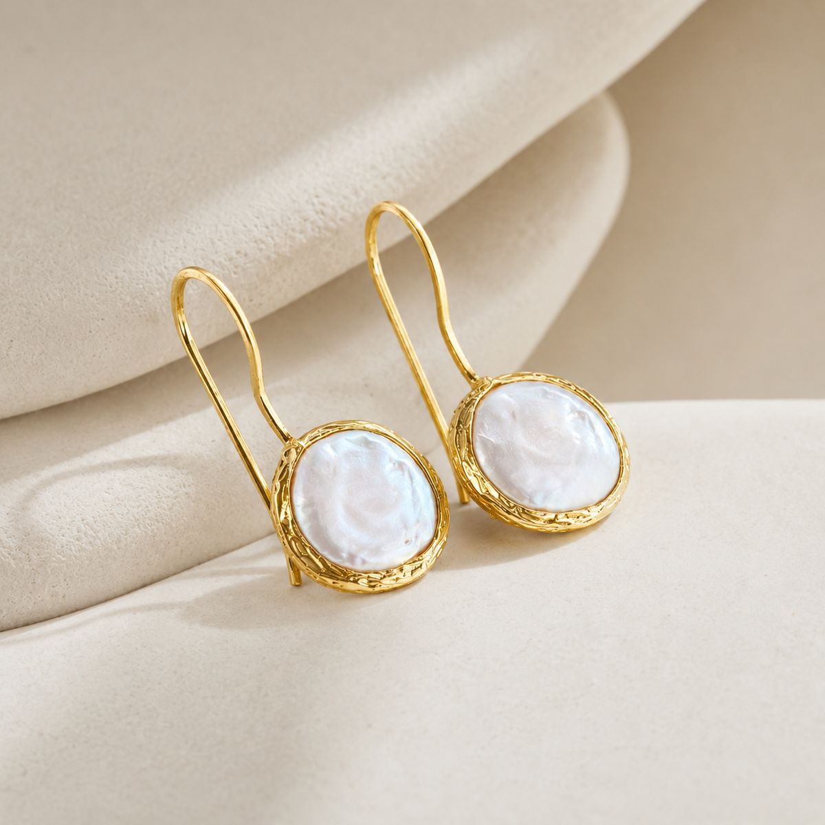 Angle view of gold-plated drop earrings with coin pearl centers.