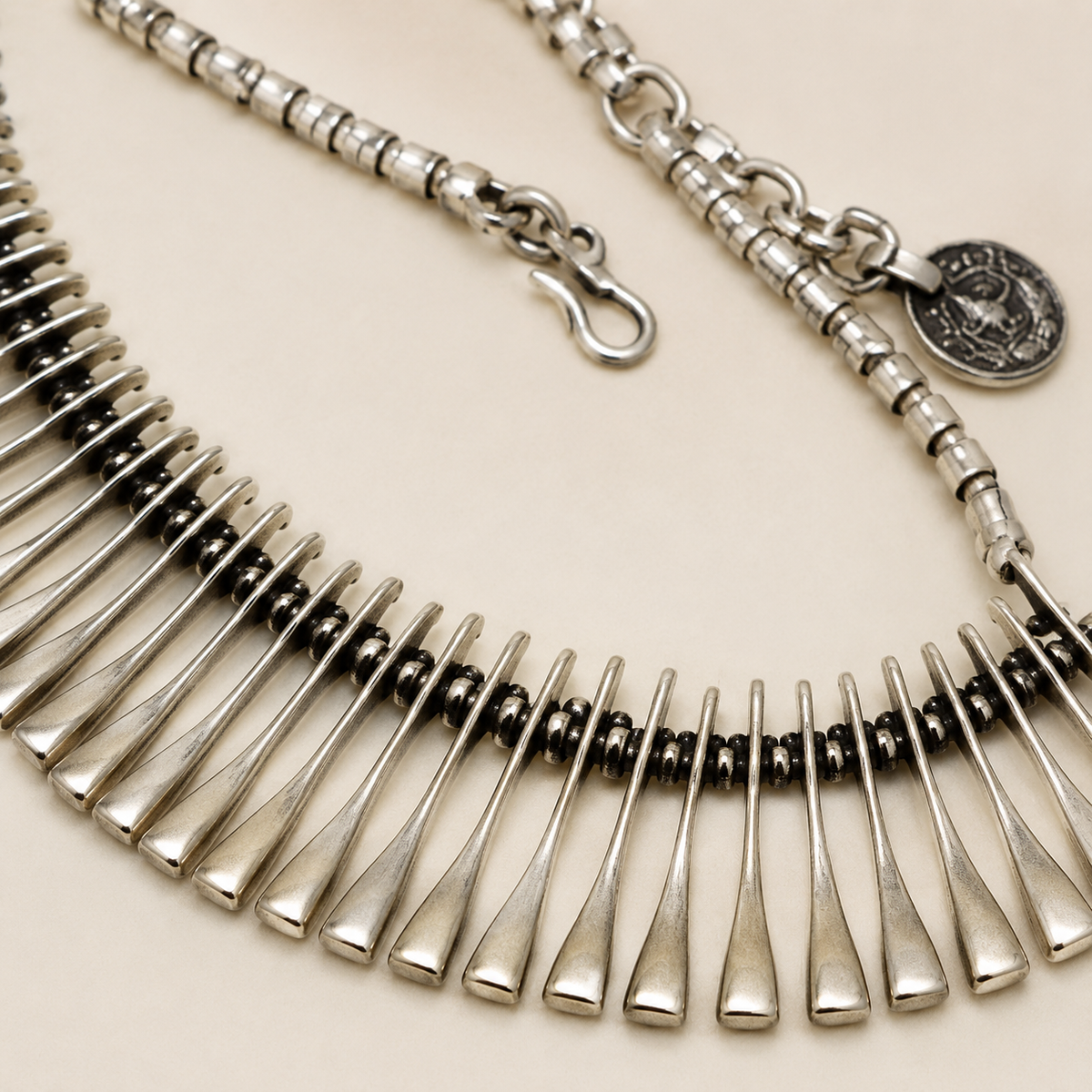 Close view of the ribbed silver-tone necklace links and fan-shaped detail.