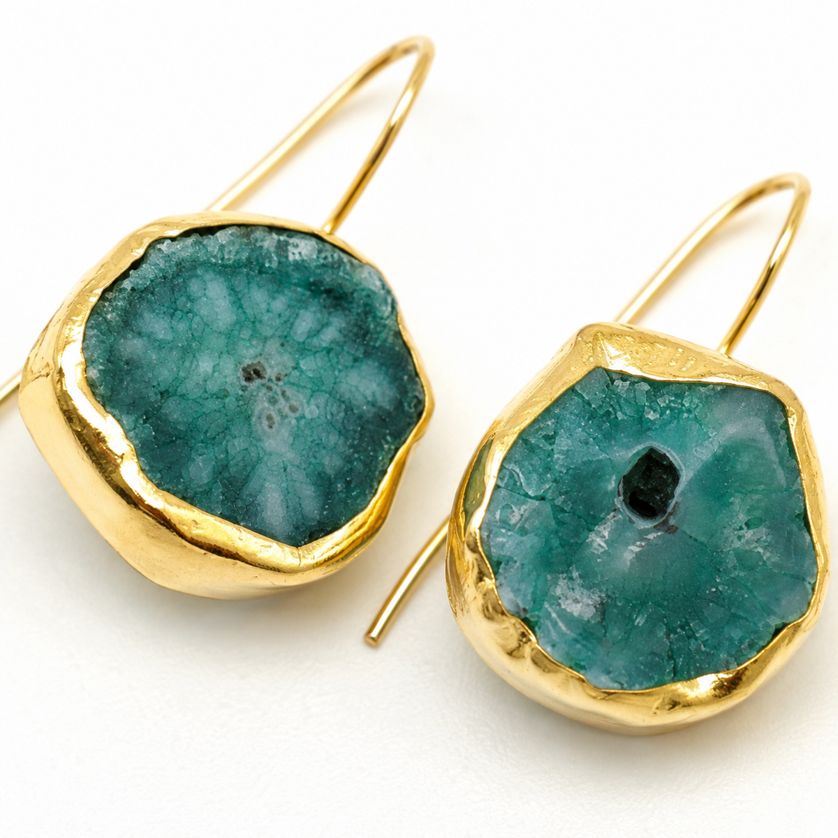 Close-up of gold-plated drop earrings with textured brown druzy mother of pearl details.