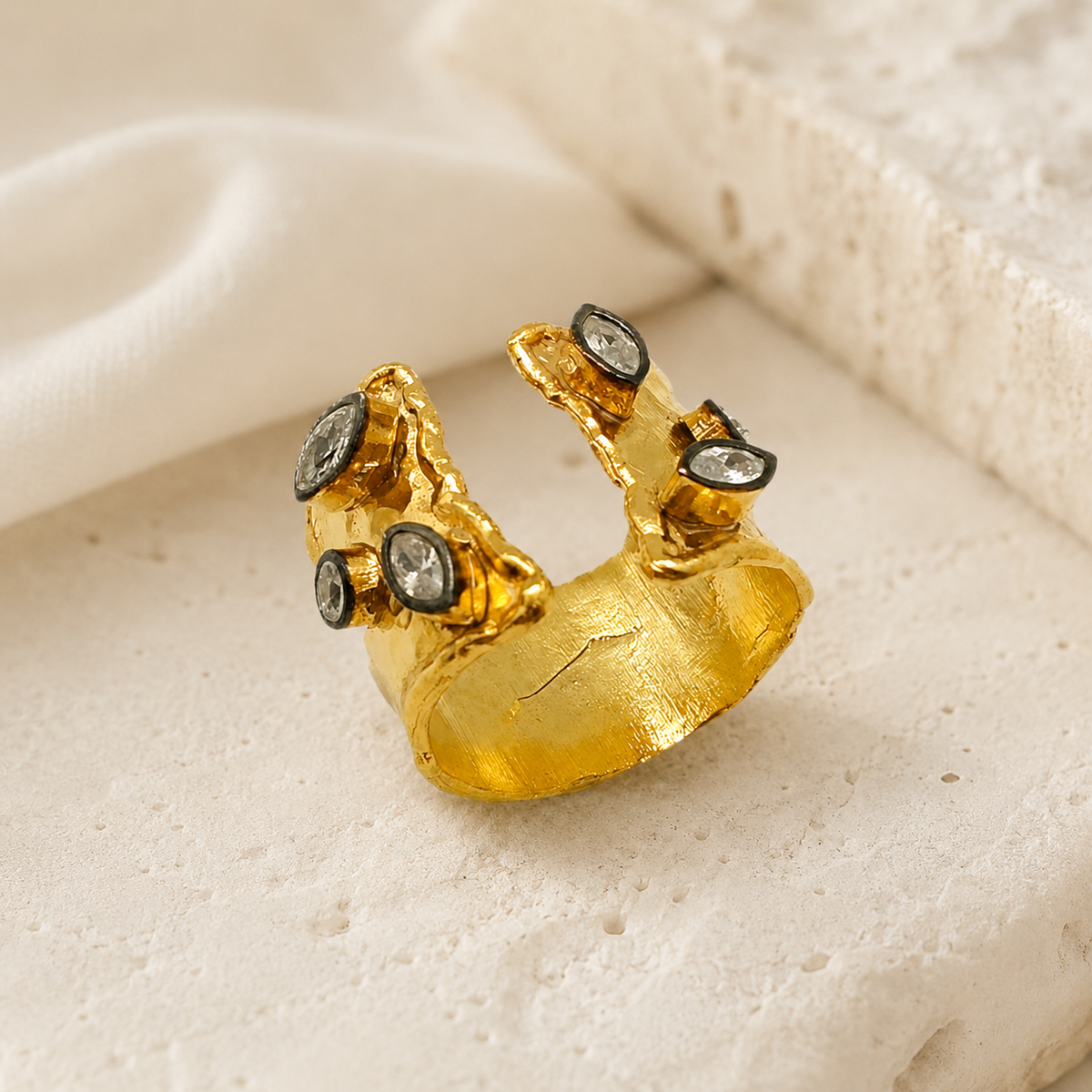 Gold-plated open cuff ring with clear quartz accents on a white background.