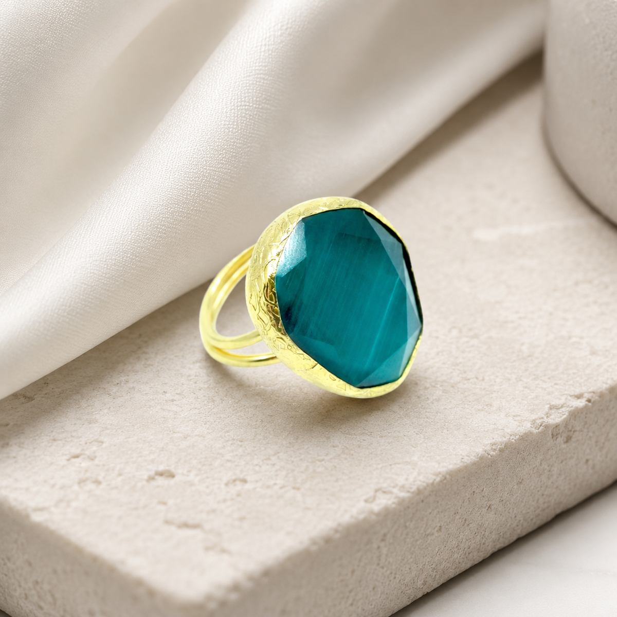 Gold-tone ring with a bold green stone and sculptural silhouette.