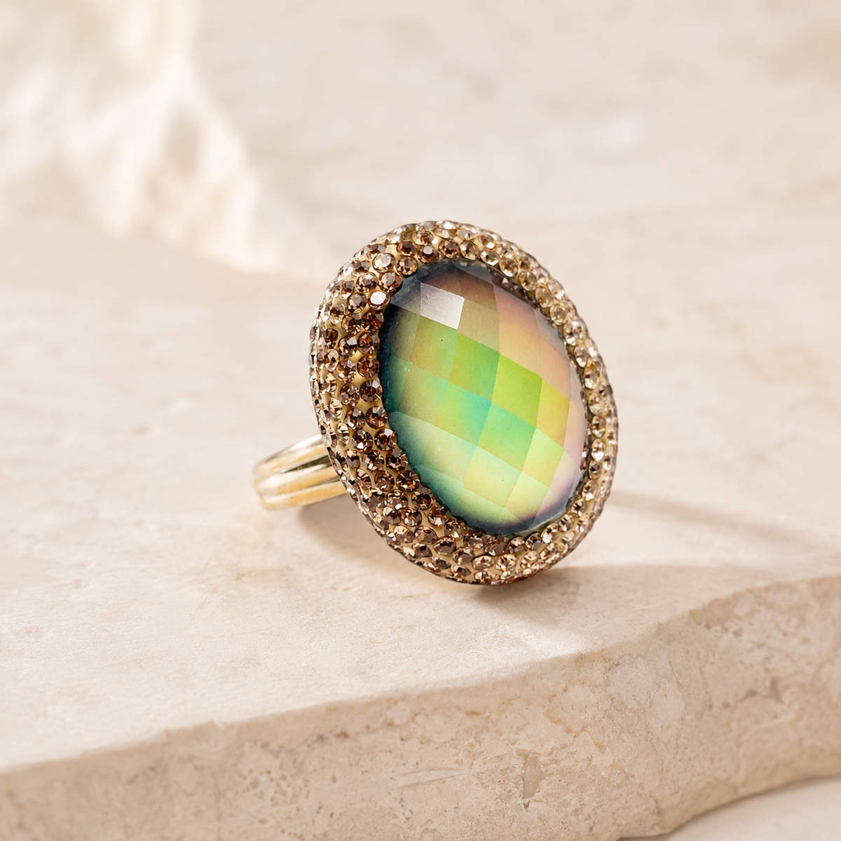 Side angle view of a gold-plated statement ring with a faceted center stone.