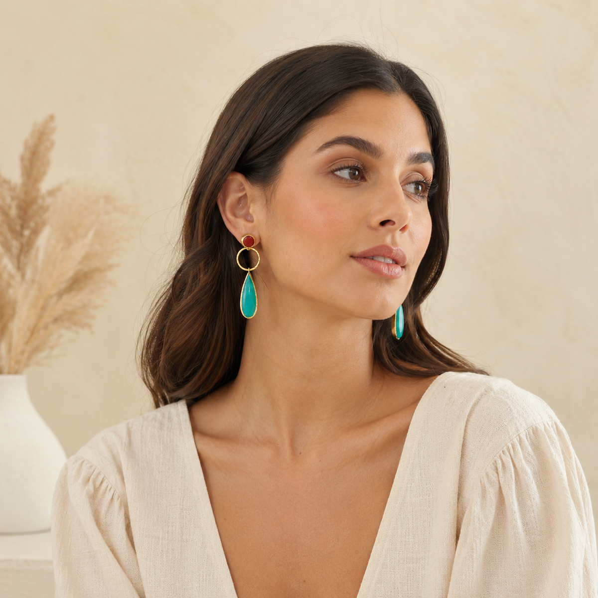 Gold-plated drop earrings with pine green leaf-shaped pendants and a small red stone top.