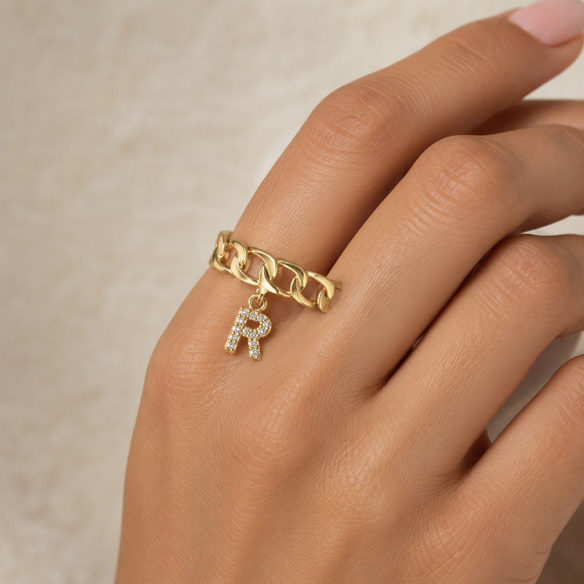 Gold-tone personalized ring with a sparkling initial pendant.