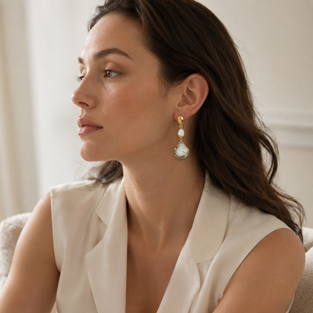 Gold-plated drop earrings with white pearl-like centers and textured stone-like pendants.