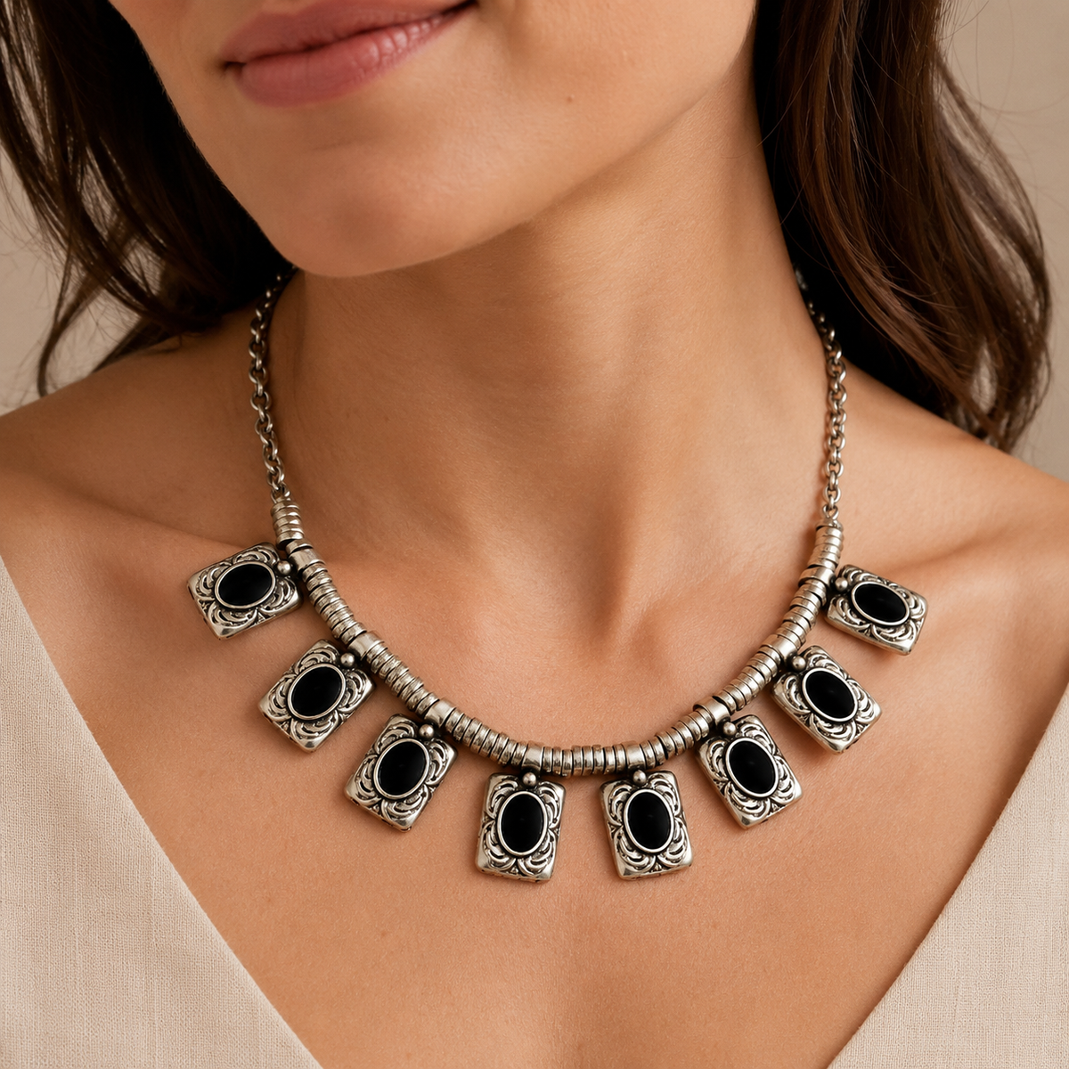 Silver-tone necklace with black oval center charms shown on a white background.