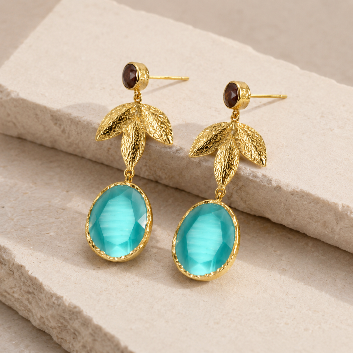 Front view of gold-tone leaf earrings with turquoise oval drops.
