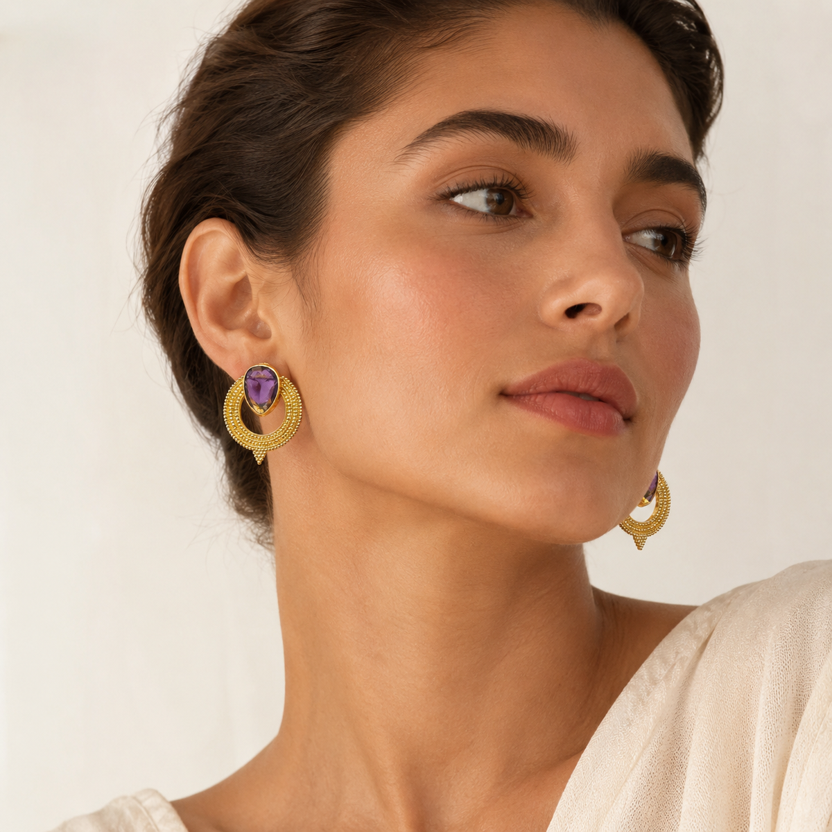 Pair of gold-plated earrings with purple CZ stones shown from the front.