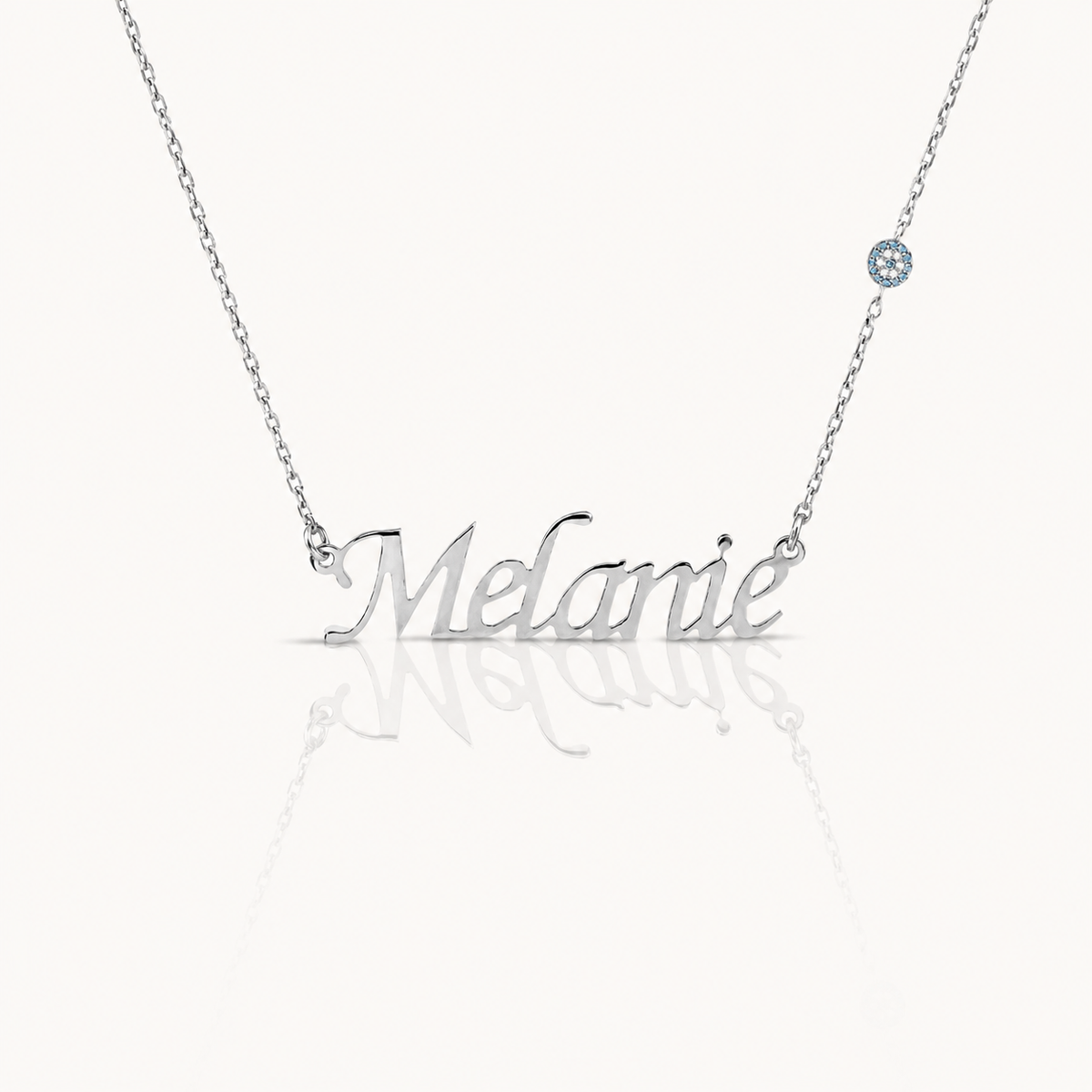 Silver-tone personalized name necklace with a polished script pendant and small blue accent.