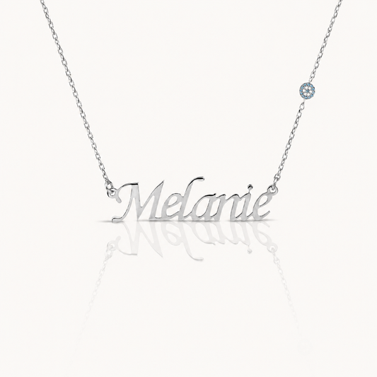Silver-tone personalized name necklace with a polished script pendant and small blue accent.