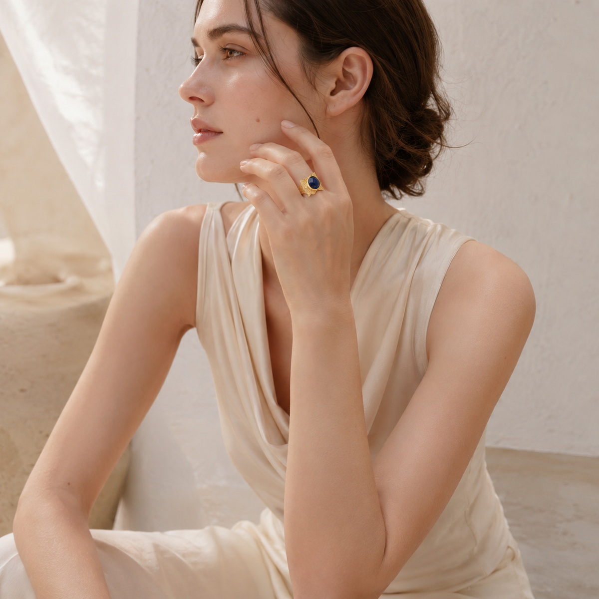 Statement ring with a faceted navy blue oval stone and sculptural gold-plated band.