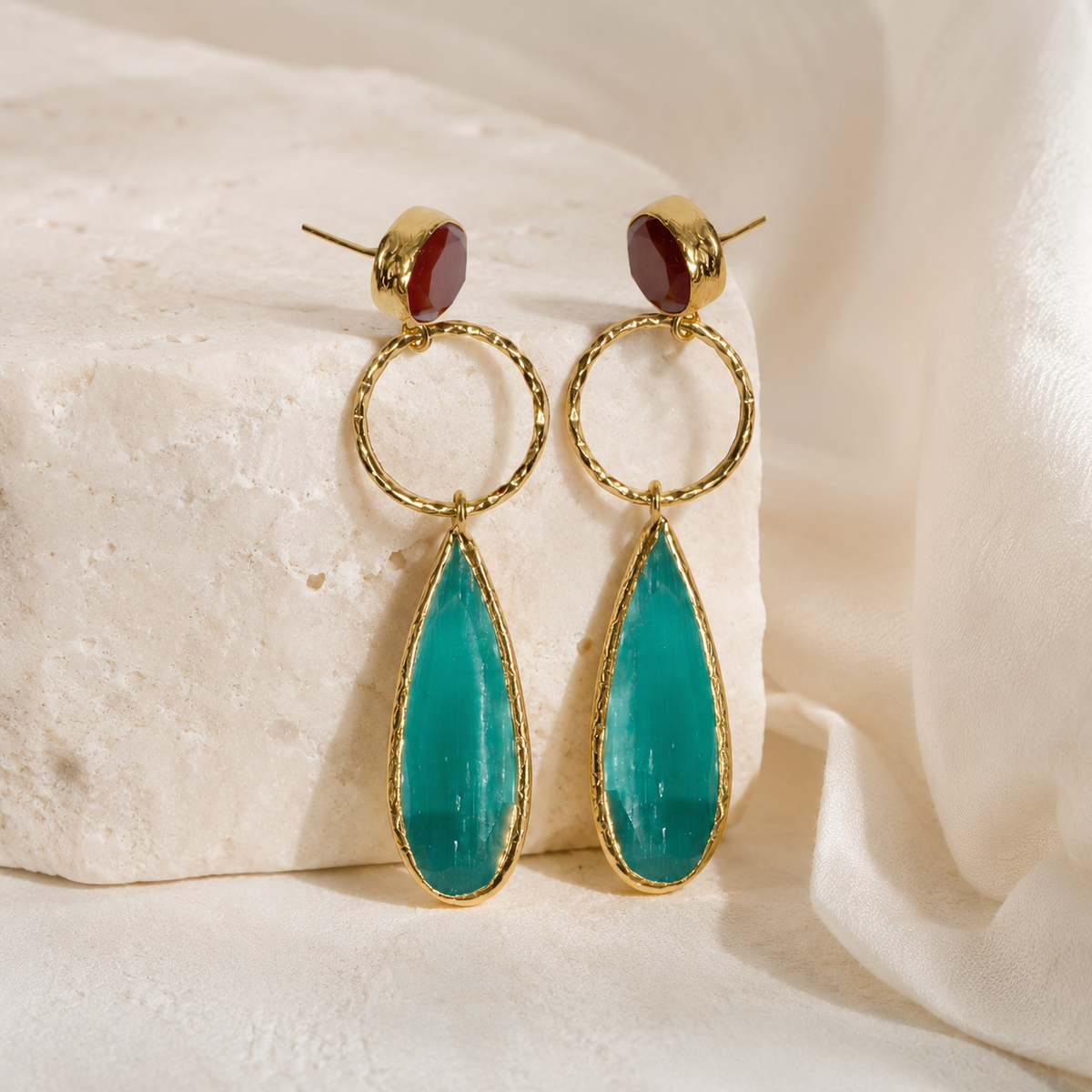 Gold-plated drop earrings with pine green leaf-shaped pendants and a small red stone top.