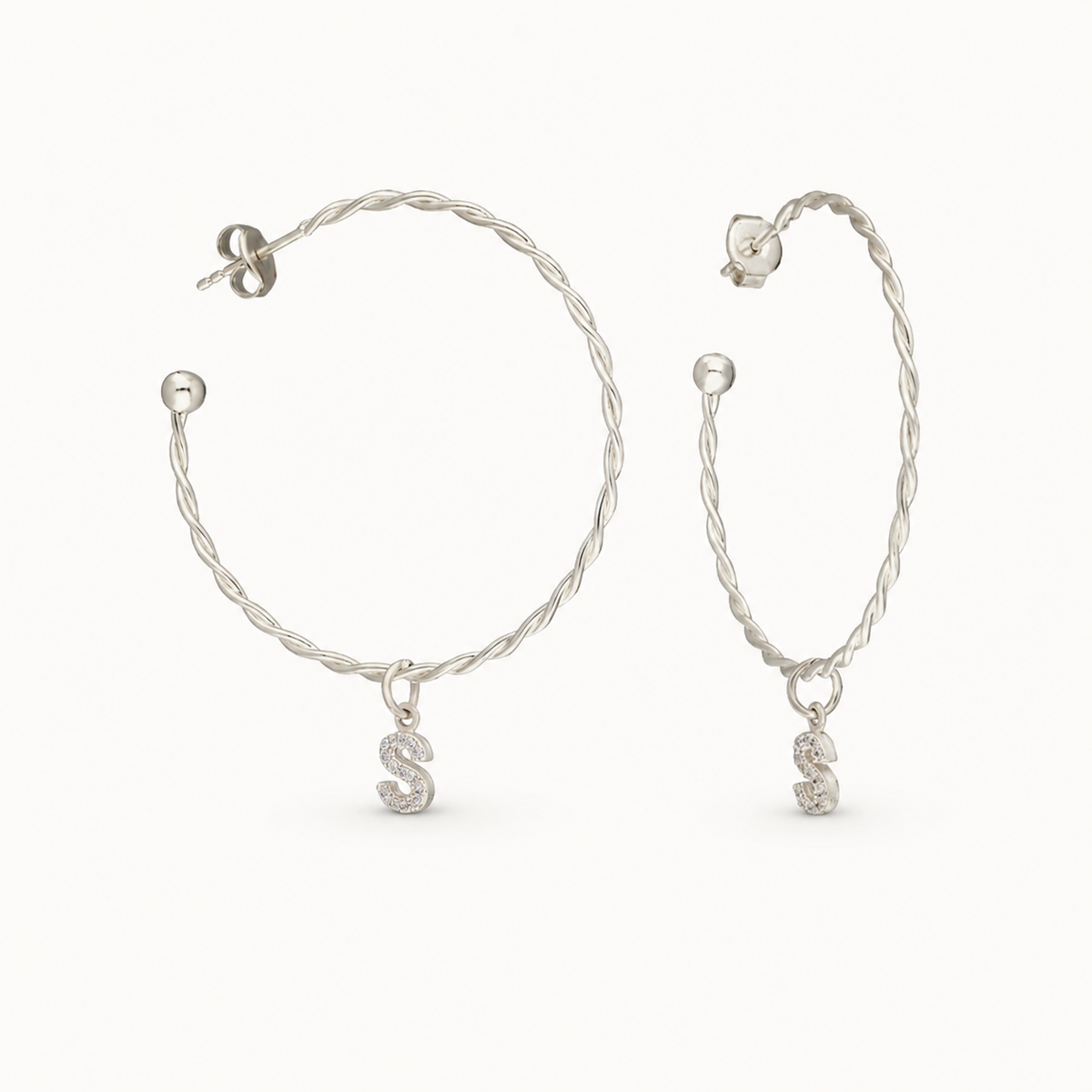 Twisted hoop earrings with a dangling CZ initial charm.