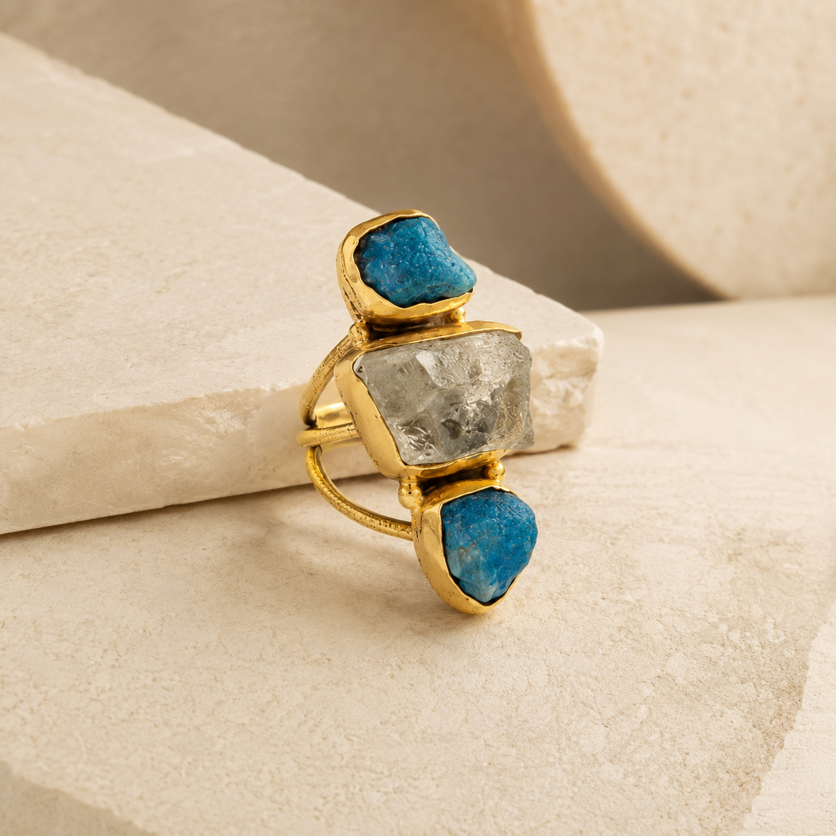 Angle view of a gold-plated ring with apatite and clear quartz stones.