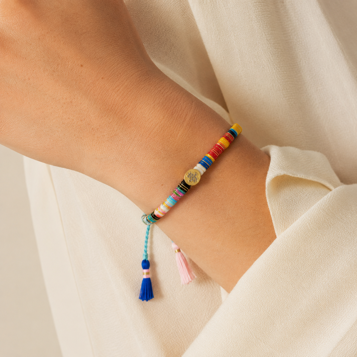 Colorful thread bracelet with a braided cord and gold-tone accents on a white background.
