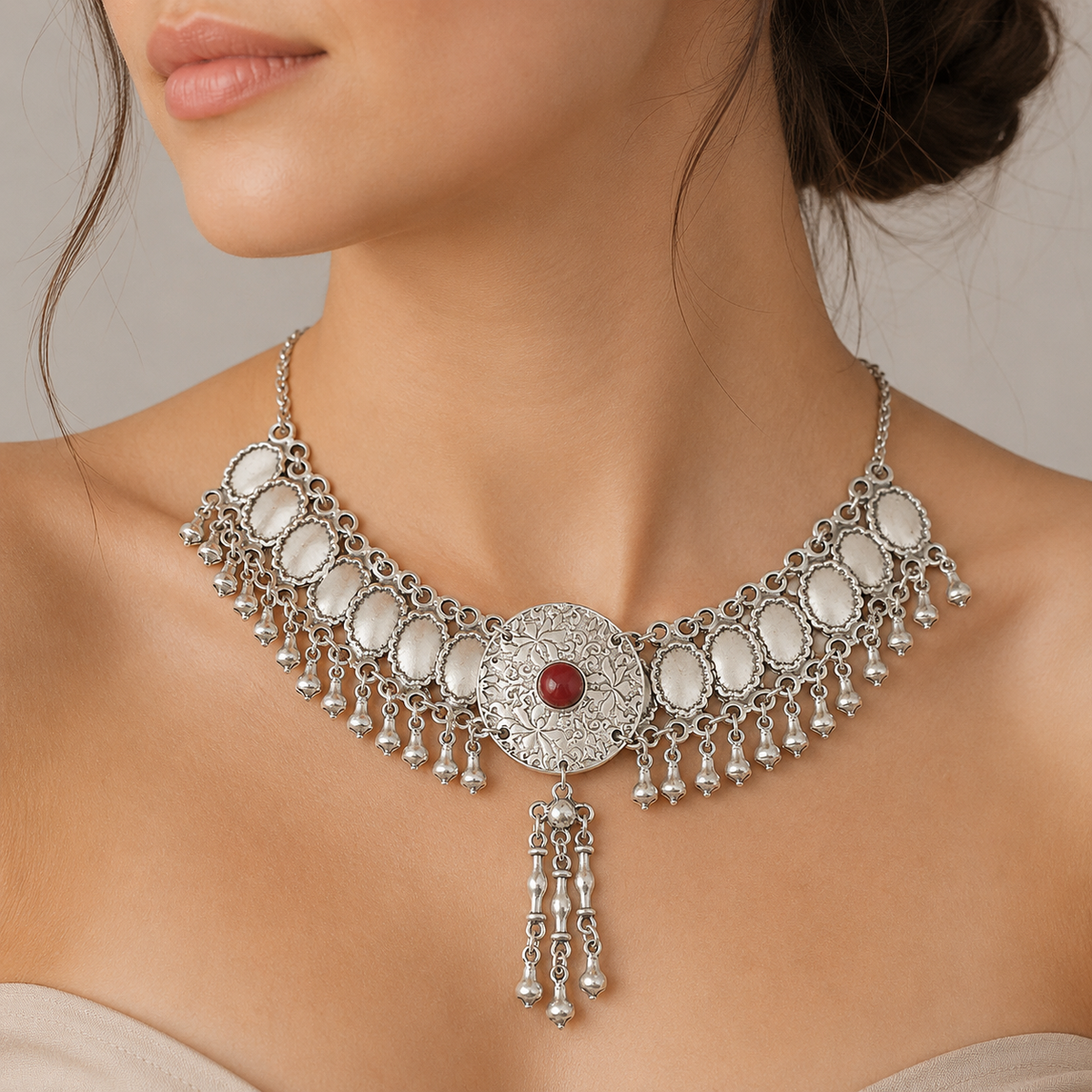 Silver-tone fringe statement necklace with a red center stone shown on a white background.