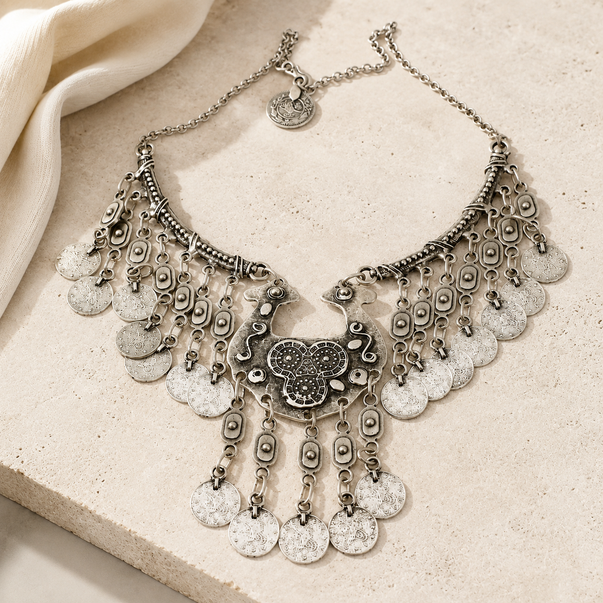 Silver statement necklace with layered coin fringe on a white background.