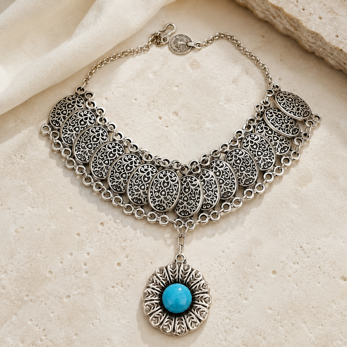 Silver-tone statement necklace with intricate filigree details and turquoise accent.