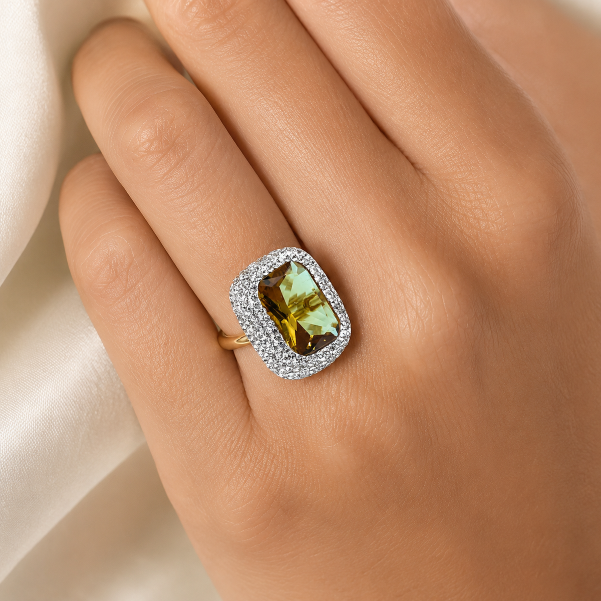 Rectangular faceted center stone ring with a sparkling halo and gold-tone band.