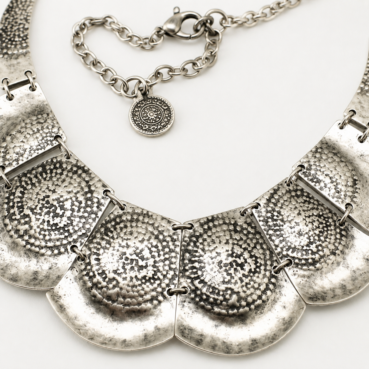 Close view of the textured hammered silver-tone plates on the necklace.