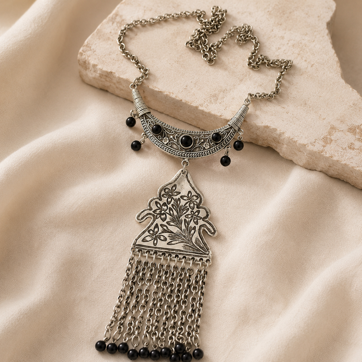 Silver-tone necklace with floral pendant and tassel chains.