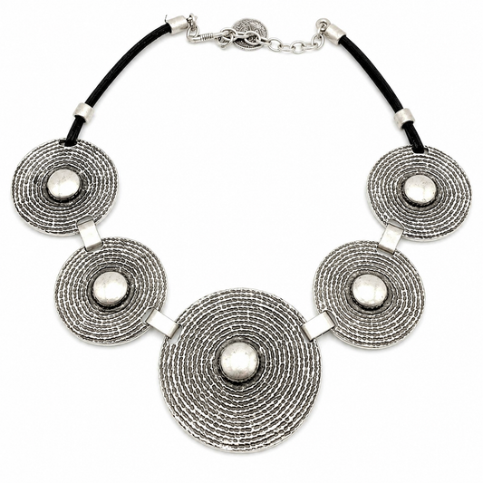 Concentric disc statement necklace with textured silver-tone discs and a black cord.