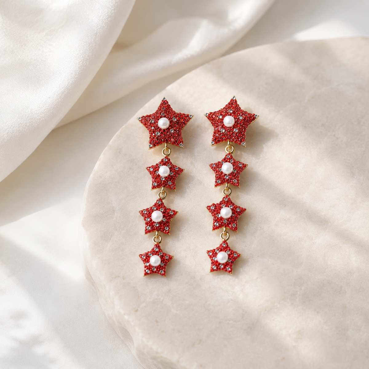Pair of red star dangle earrings with pearl-like centers and gold-tone finish.