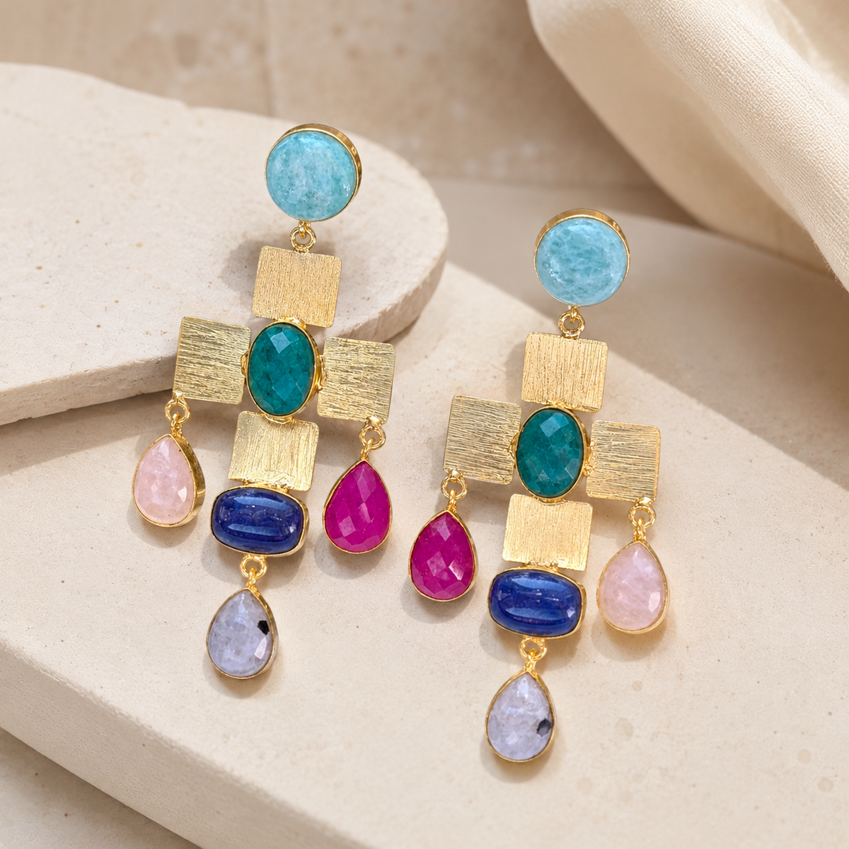Gold-plated statement earrings shown at an angle with a cross-shaped mosaic design and colorful stone accents.