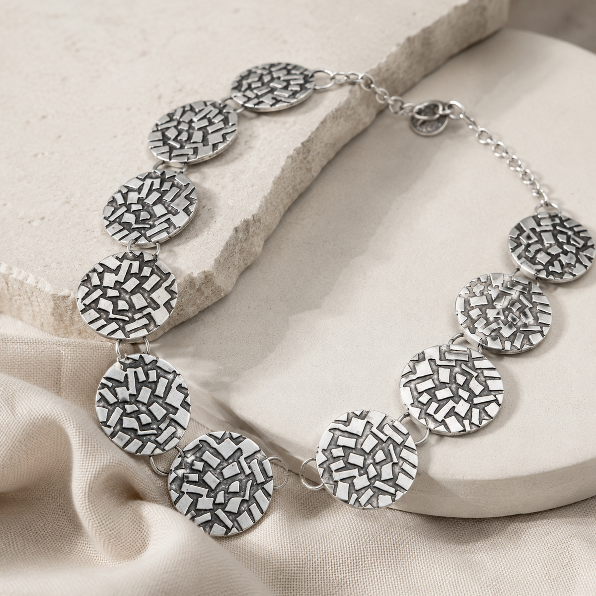 Angle view of the silver textured disc necklace.