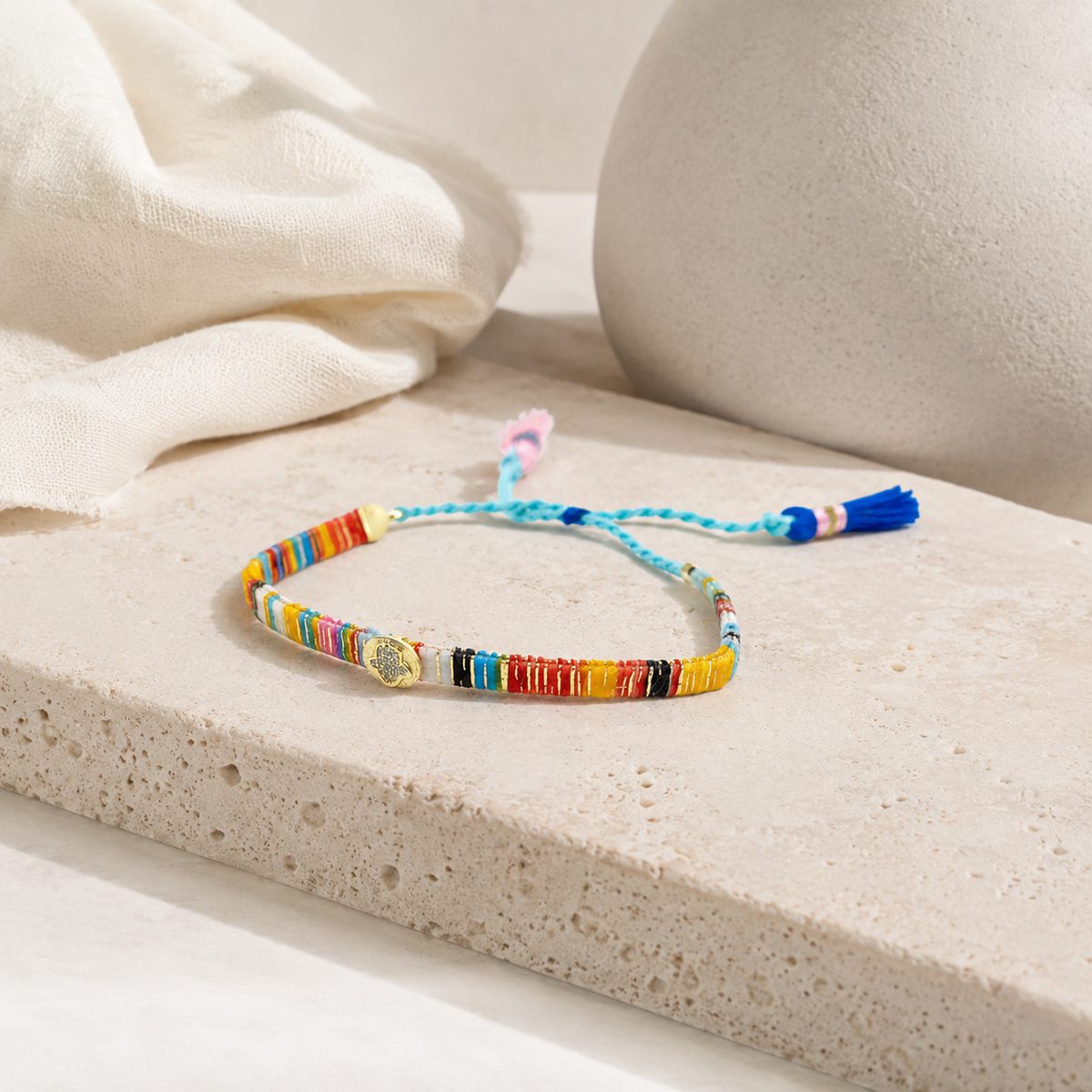Colorful thread bracelet with braided cord and tassel ends on a white background.