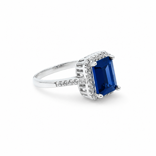 Cushion cut blue sapphire ring with a silver-tone setting and sparkling accents.