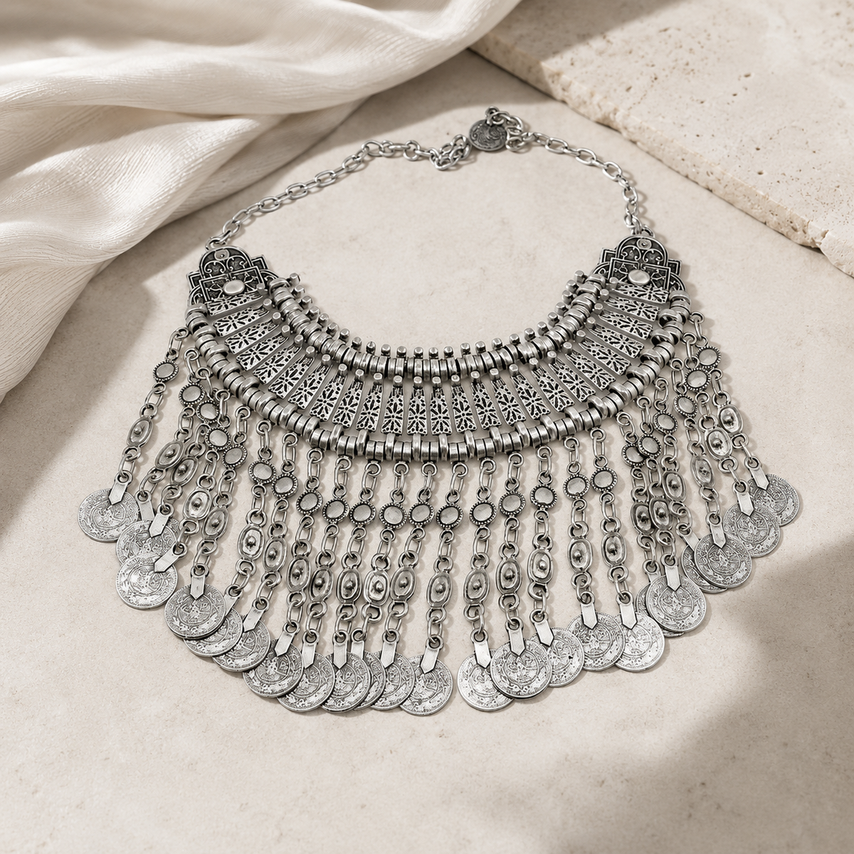 Boho-inspired silver-tone necklace with layered fringe and coin charms.
